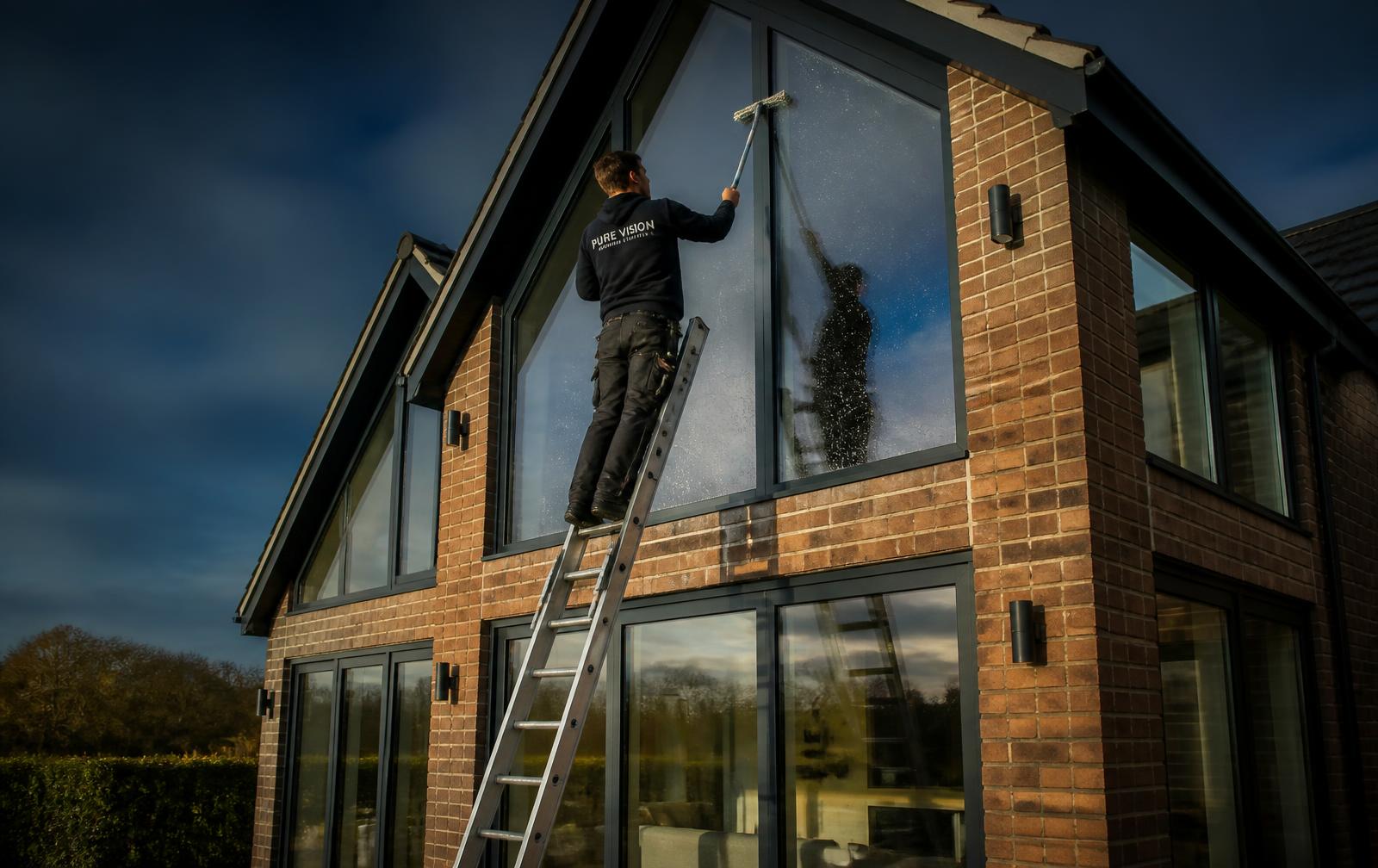 Window cleaner using a pole to clean the upstairs windows of a house